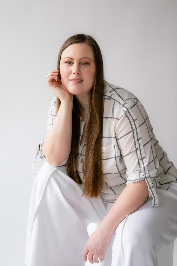 Annie Doran fondatrice de Clair Obscur Design, designer d'intérieur virtuel, design intérieur Canada, organisation maison, décoration Airbnb, habillée en blanc sur décor uni blanc.