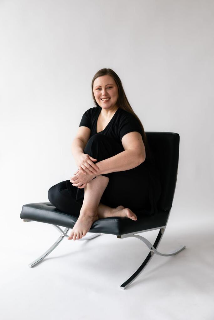 Clair Obscur Design, designer d'intérieur virtuel, design intérieur Canada, organisation maison, décoration Airbnb, Annie Doran fondatrice habillée en noire, sur une chaise noire et décor minimaliste blanc, page À propos.