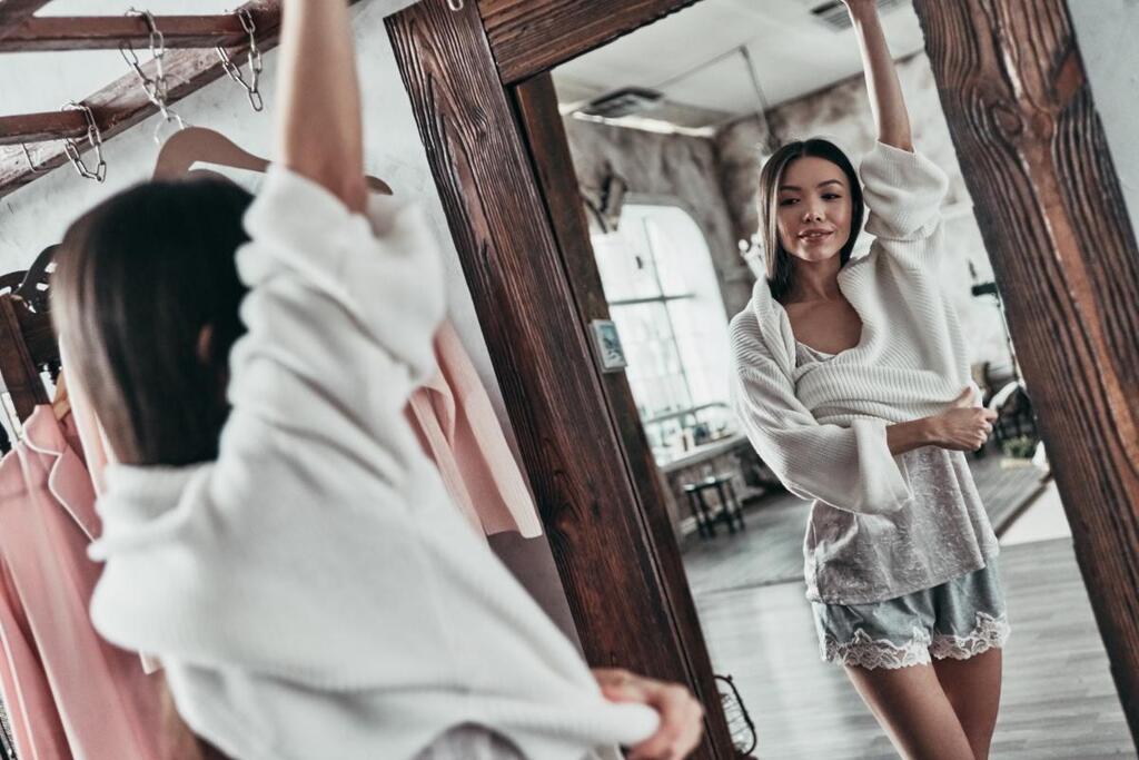 Clair Obscur Design, design d'intérieur virtuel, organisation maison, désencombrement vêtement, dressing, femme qui se sent bien dans ses vêtements, elle se regarde sur un grand miroir sur pied, cadre en bois rustique.